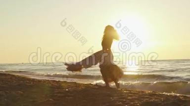 年轻迷人的女孩，穿着长长的浅色连衣裙，在金色的日落光线照射下，在沙滩上旋转
